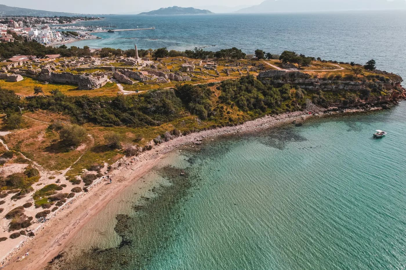 Aerial view of ancient ruins on Aegina's coast, with the town and harbour beyond