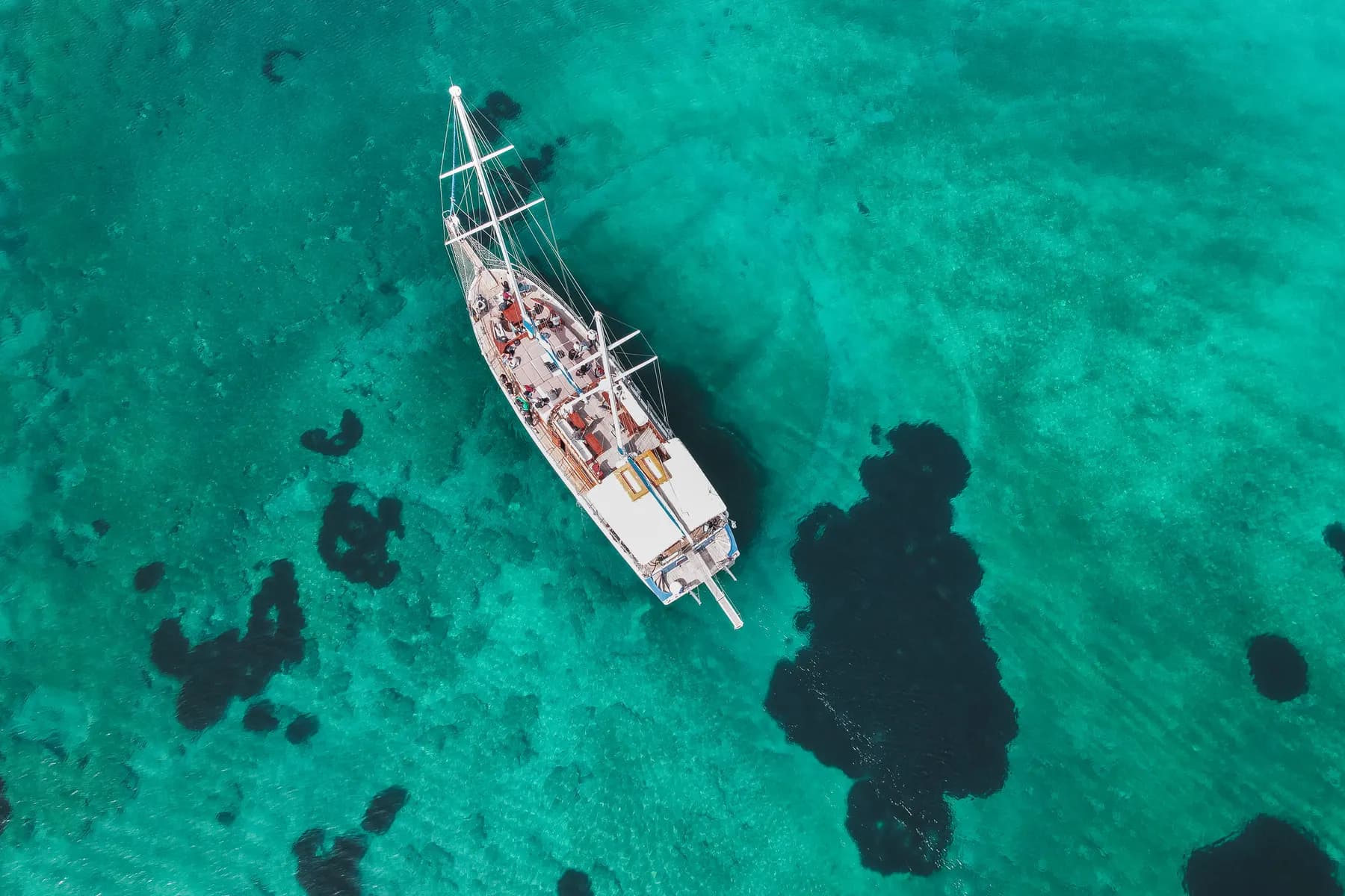 Aerial view of the boat anchored over a reef in clear turquoise water