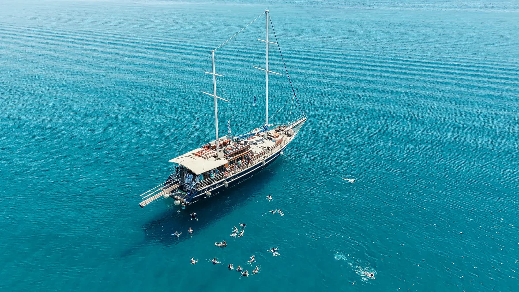 Aerial view of guests swimming beside the anchored boat