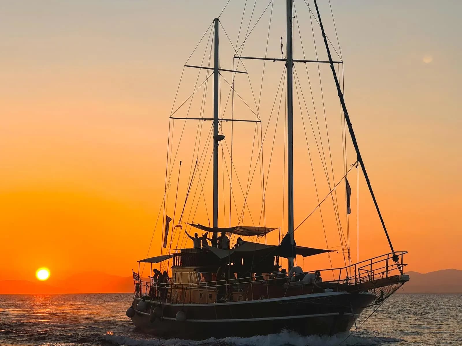 The boat silhouetted against a golden sunset in the Saronic Gulf